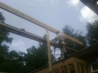 Carpenter setting a ridge beam over a new addition frame — Ice Dam Removal by Roofing Brothers in Windsor Mill