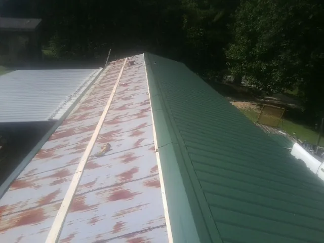 Old rusted panels beside newly installed green metal roofing — Wind Damage Roof Repair by Roofing Brothers in Windsor Mill