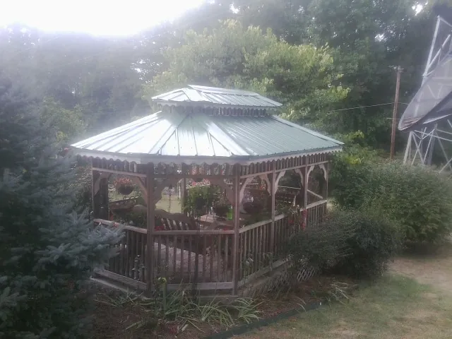 Green metal roof on a backyard gazebo surrounded by garden beds in Windsor Mill