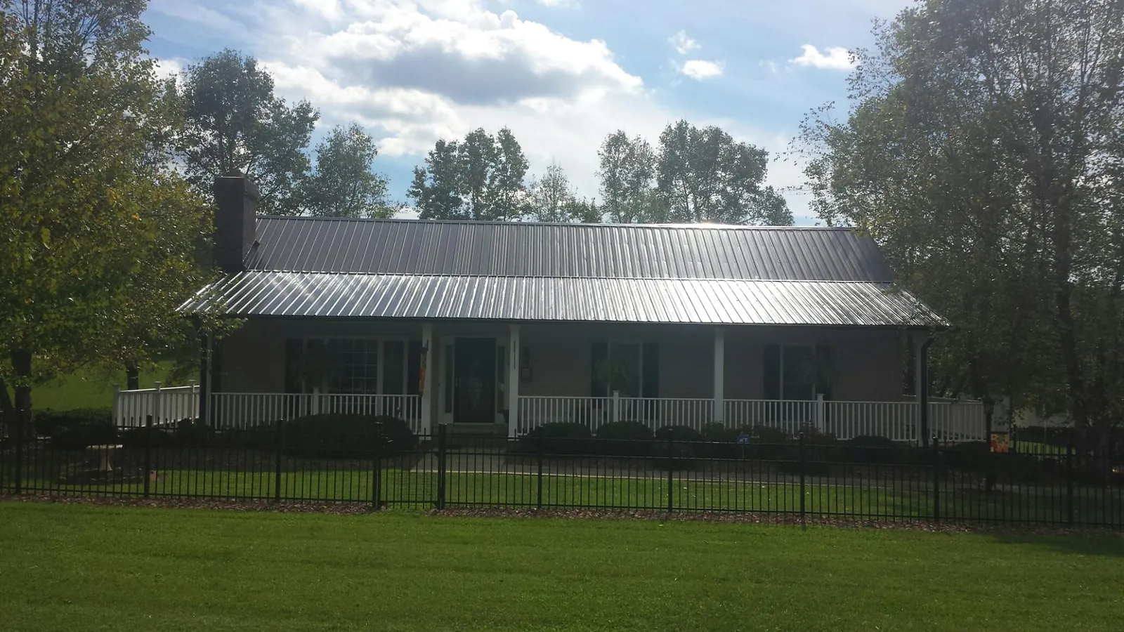 Gray metal roof on a brick ranch with a full width front porch — Gutter Guard Installation work by our crew in Windsor Mill
