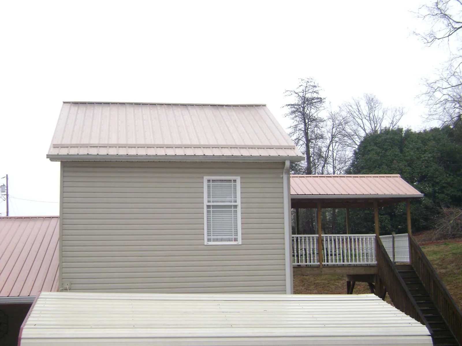 Tan metal roofs on a two story addition and attached porch, from a Roof Replacement job in Windsor Mill